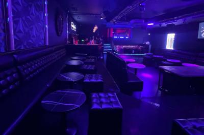 Entrée d'un club nocturne avec enseigne lumineuse ’Infinity Club’ et porte ornée de motifs décoratifs.