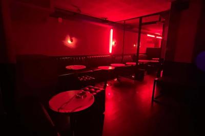 Entrée d'un club nocturne avec enseigne lumineuse ’Infinity Club’ et porte ornée de motifs décoratifs.