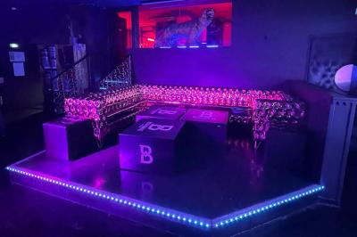 Entrée d'un club nocturne avec enseigne lumineuse ’Infinity Club’ et porte ornée de motifs décoratifs.