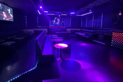 Entrée d'un club nocturne avec enseigne lumineuse ’Infinity Club’ et porte ornée de motifs décoratifs.