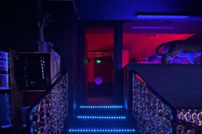 Entrée d'un club nocturne avec enseigne lumineuse ’Infinity Club’ et porte ornée de motifs décoratifs.