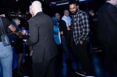 Façade d'un club nocturne avec enseigne lumineuse ’Infinity Club’ et porte ornée de motifs décoratifs.