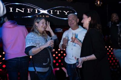 Façade d'un club nocturne avec enseigne lumineuse ’Infinity Club’ et porte ornée de motifs décoratifs.