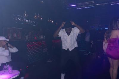 Façade d'un club nocturne avec enseigne lumineuse ’Infinity Club’ et porte ornée de motifs décoratifs.