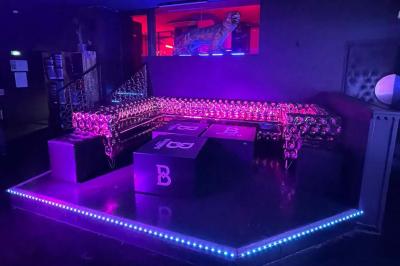 Façade d'un club nocturne avec enseigne lumineuse ’Infinity Club’ et porte ornée de motifs décoratifs.