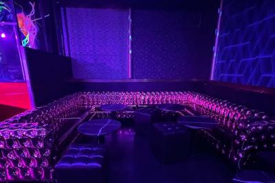 Façade d'un club nocturne avec enseigne lumineuse ’Infinity Club’ et porte ornée de motifs décoratifs.