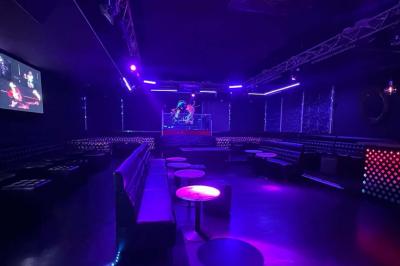 Façade d'un club nocturne avec enseigne lumineuse ’Infinity Club’ et porte ornée de motifs décoratifs.