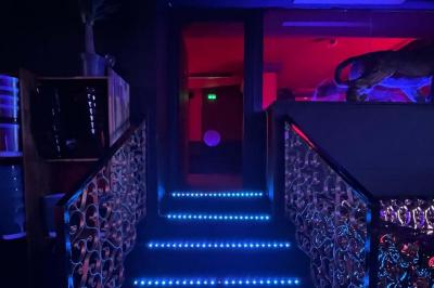 Façade d'un club nocturne avec enseigne lumineuse ’Infinity Club’ et porte ornée de motifs décoratifs.