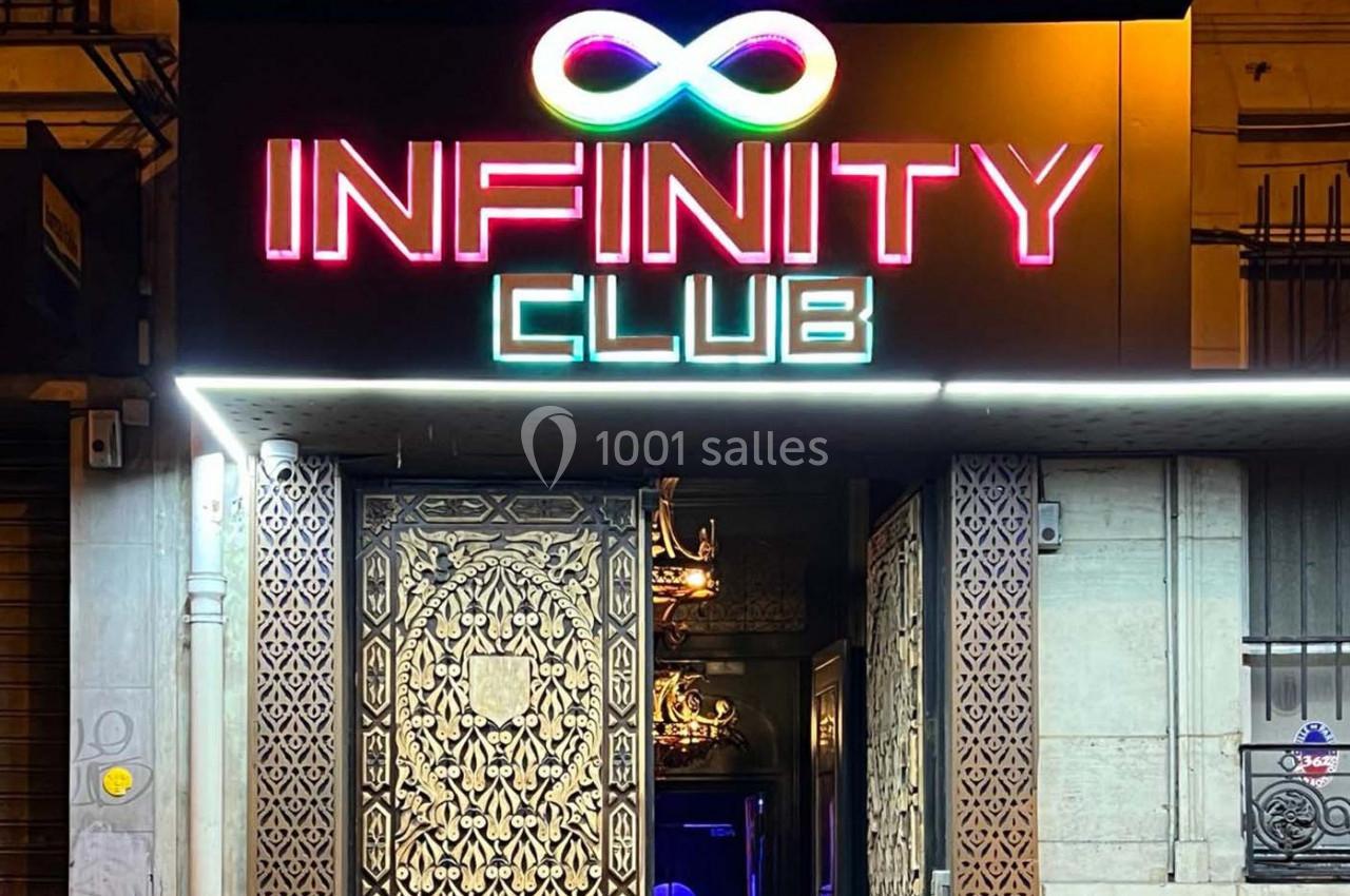 Façade d'un club nocturne avec enseigne lumineuse ’Infinity Club’ et porte ornée de motifs décoratifs.