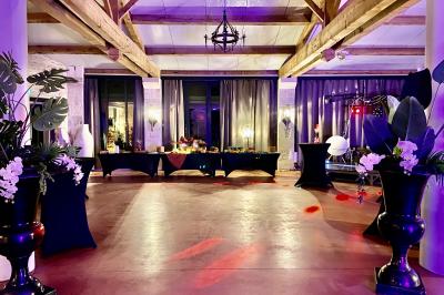 Manoir éclairé de nuit avec des lumières colorées, tables dressées et invités rassemblés dans un jardin.