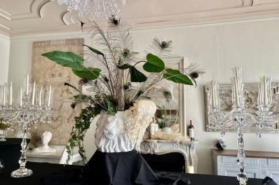 Manoir éclairé de nuit avec des lumières colorées, tables dressées et invités rassemblés dans un jardin.