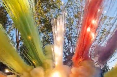 Un homme en costume bleu tient un saxophone sous une pergola décorée de fleurs blanches.