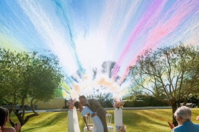 Un homme en costume bleu tient un saxophone sous une pergola décorée de fleurs blanches.
