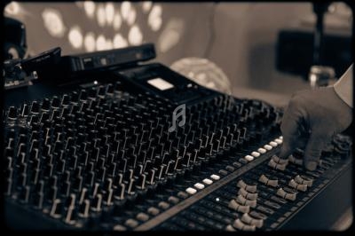 Main ajustant les curseurs d'une console de mixage audio dans un environnement faiblement éclairé.