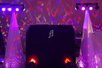 Installation de matériel de sonorisation et éclairage coloré avec projecteurs et effets lumineux dans une salle.