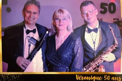 Trois personnes posent en tenue de soirée, deux hommes tenant des instruments de musique et une femme au centre.