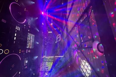 Vue d'une console DJ éclairée par des lumières colorées et des faisceaux laser dans une ambiance de soirée.