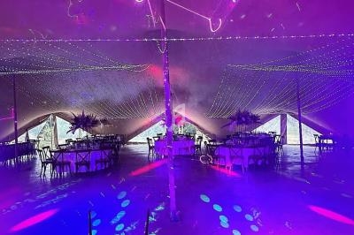 Vue depuis une table de mixage sur une salle décorée avec des lumières colorées et des lasers, ambiance festive.