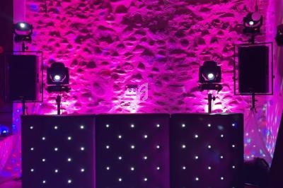 Salle en pierre éclairée par des lumières roses et violettes, avec une table lumineuse et des équipements audio-visuels.