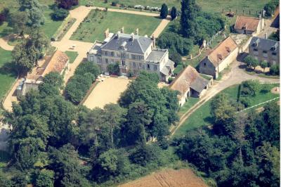 Alignement d'arbres taillés devant un bâtiment en pierre avec des fenêtres et des portes visibles.