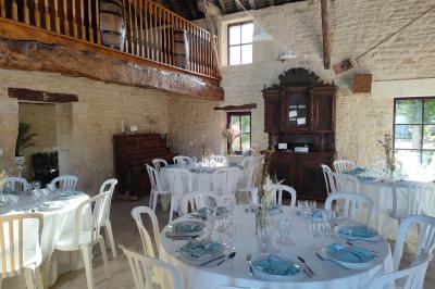 Alignement d'arbres taillés devant un bâtiment en pierre avec des fenêtres et des portes visibles.