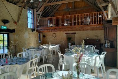 Alignement d'arbres taillés devant un bâtiment en pierre avec des fenêtres et des portes visibles.