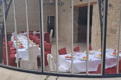 Alignement d'arbres taillés devant un bâtiment en pierre avec des fenêtres et des portes visibles.