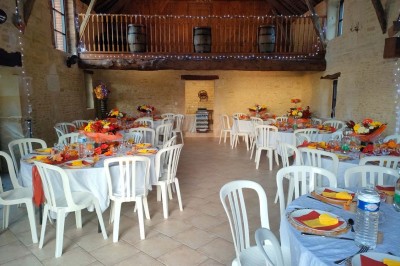 Table en bois rustique dressée pour un repas, avec vaisselle fleurie, bougies, rondins de bois et chemin de table vert.