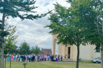 Table en bois rustique dressée pour un repas, avec vaisselle fleurie, bougies, rondins de bois et chemin de table vert.