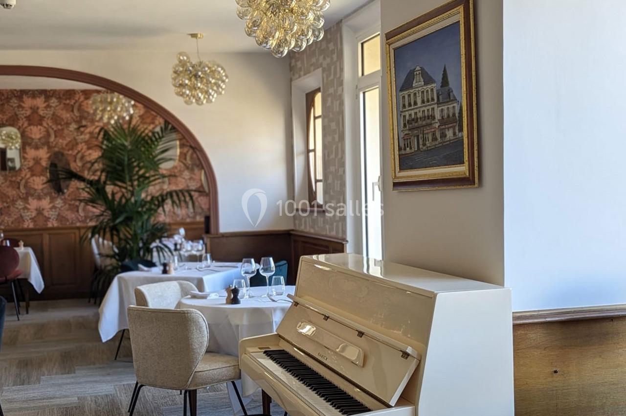 Un piano blanc dans un restaurant élégant avec des tables dressées et une décoration lumineuse et raffinée.