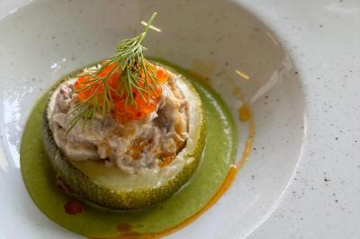 Une assiette contenant une préparation de poisson effiloché avec des herbes, accompagnée de trois points de purée verte.