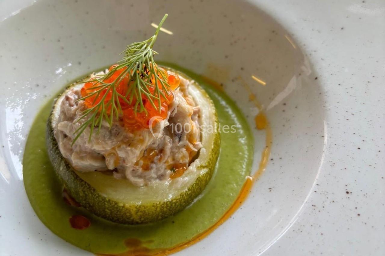 Tranche de courgette garnie de rillettes, œufs de poisson et aneth, posée sur une sauce verte.