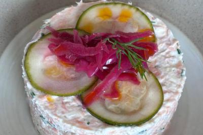 Une assiette contenant une préparation de poisson effiloché avec des herbes, accompagnée de trois points de purée verte.