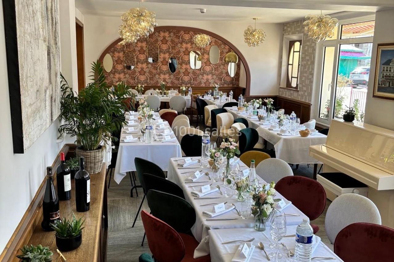 Salle de restaurant élégamment décorée avec des tables dressées pour un repas, entourées de chaises colorées.