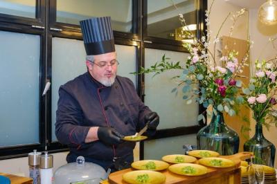 Salle décorée avec des ballons roses, éclairage violet, deux personnes marchant au centre, tables hautes et chaises…