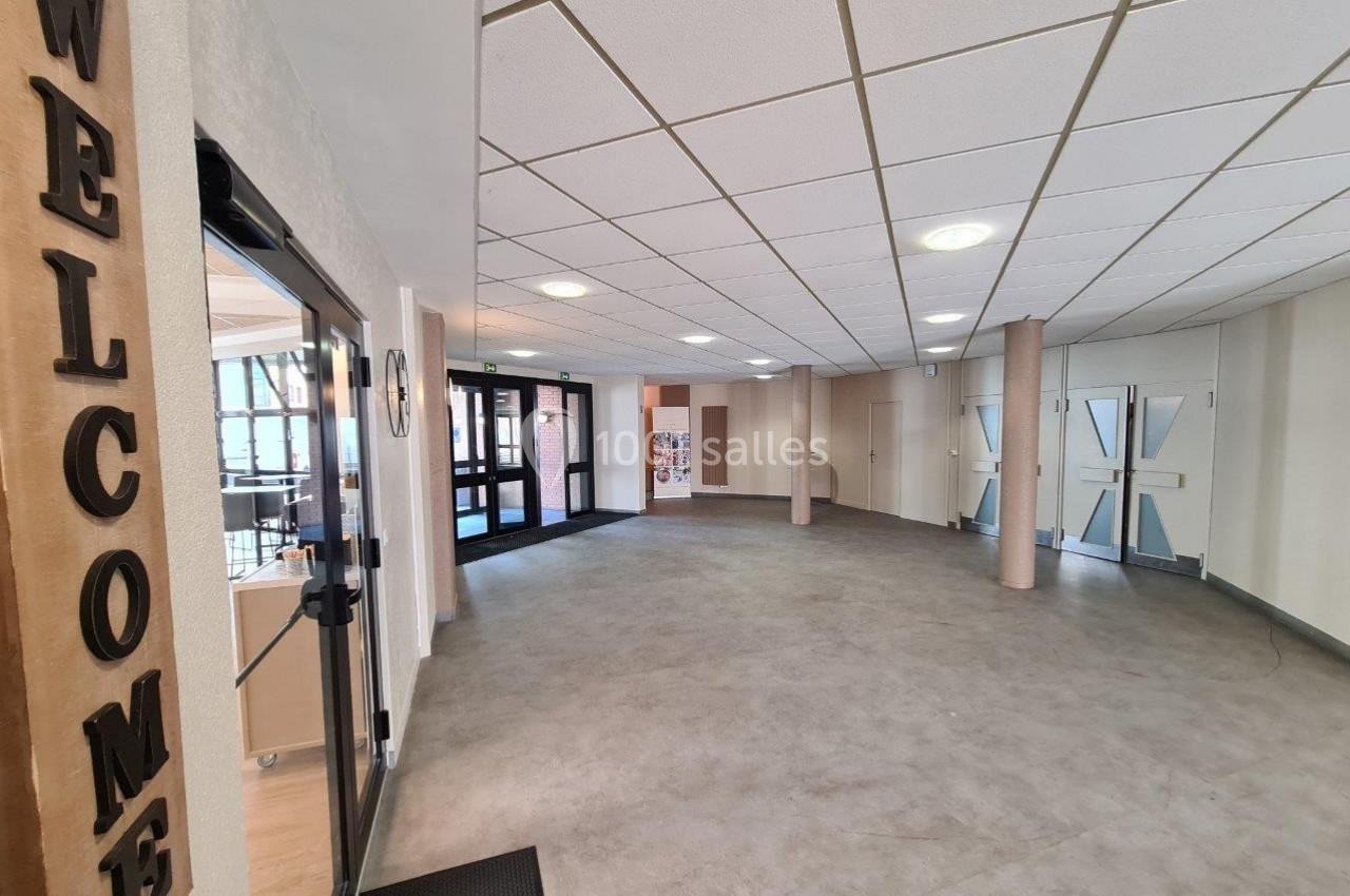 Entrée d'un bâtiment avec sol en carrelage, portes vitrées, panneau ’Welcome’ en bois et lumière naturelle.