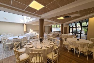 Salle décorée avec des ballons roses, éclairage violet, deux personnes marchant au centre, tables hautes et chaises…