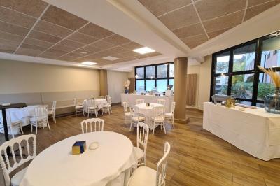 Salle décorée avec des ballons roses, éclairage violet, deux personnes marchant au centre, tables hautes et chaises…