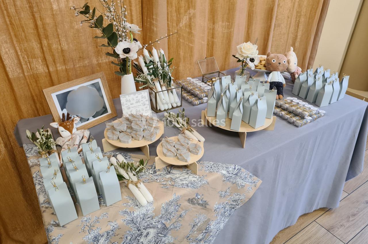 Table décorée avec des boîtes cadeaux bleu pastel, des fleurs et des friandises pour une réception ou célébration.