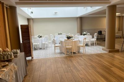 Salle décorée avec des ballons roses, éclairage violet, deux personnes marchant au centre, tables hautes et chaises…