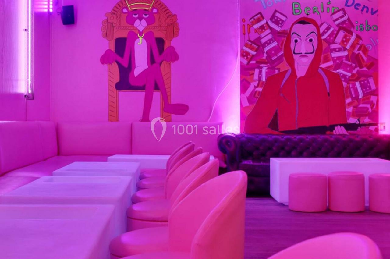 Salle rose avec des banquettes, des chaises et des peintures murales représentant des personnages fictifs.