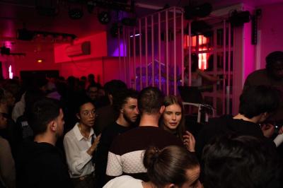 Salle de bar aux murs roses avec banquettes blanches, tabourets assortis et néons décoratifs.