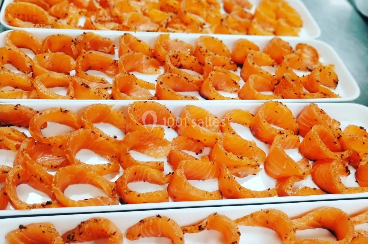 Tranches de saumon marinées disposées en rangées sur des plateaux blancs.