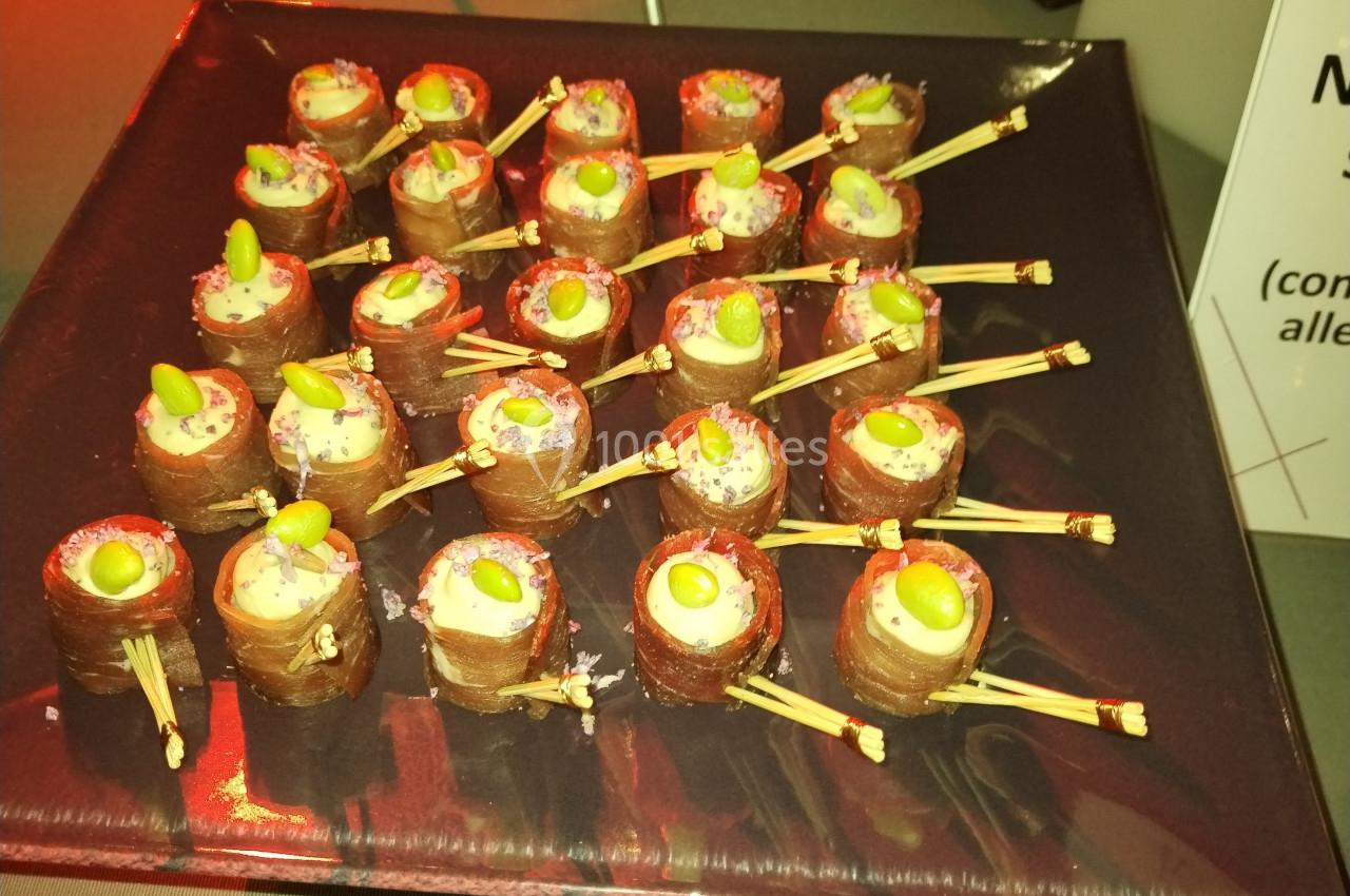 Plateau de bouchées apéritives enroulées de chocolat, garnies de crème et décorées de fruits ou graines.