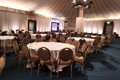 Baby-foot géant installé dans un espace intérieur avec éclairage tamisé et tables hautes en arrière-plan.