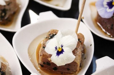 Petits pains garnis de pastrami, germes de luzerne et graines noires, disposés sur un plateau en métal.