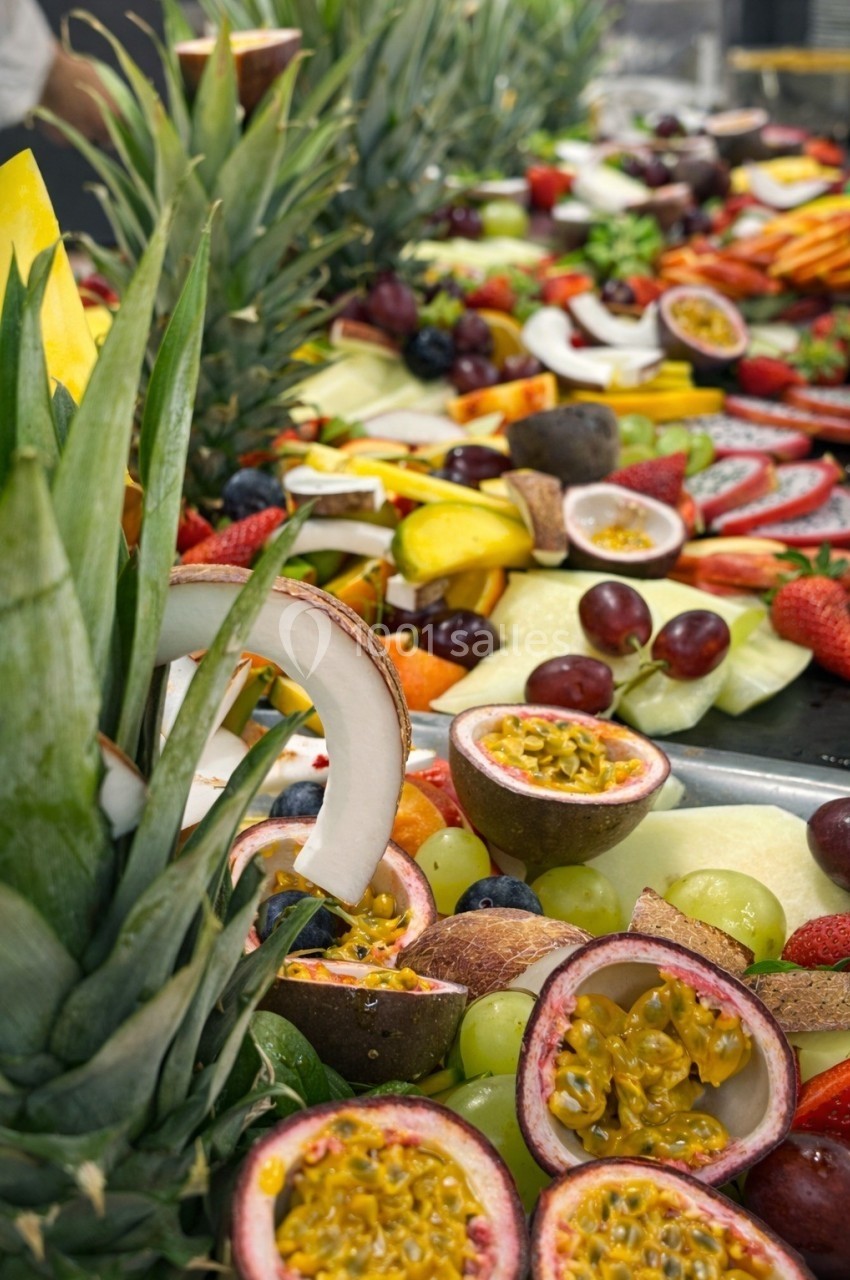 Plateau de fruits variés comprenant ananas, fruits de la passion, fraises, raisins et morceaux de noix de coco.