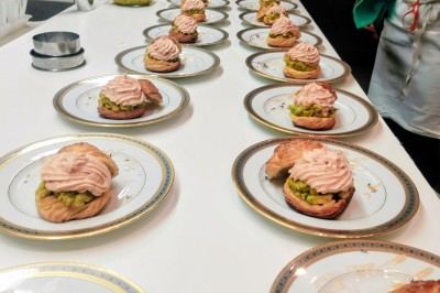 Petits pains garnis de pastrami, germes de luzerne et graines noires, disposés sur un plateau en métal.