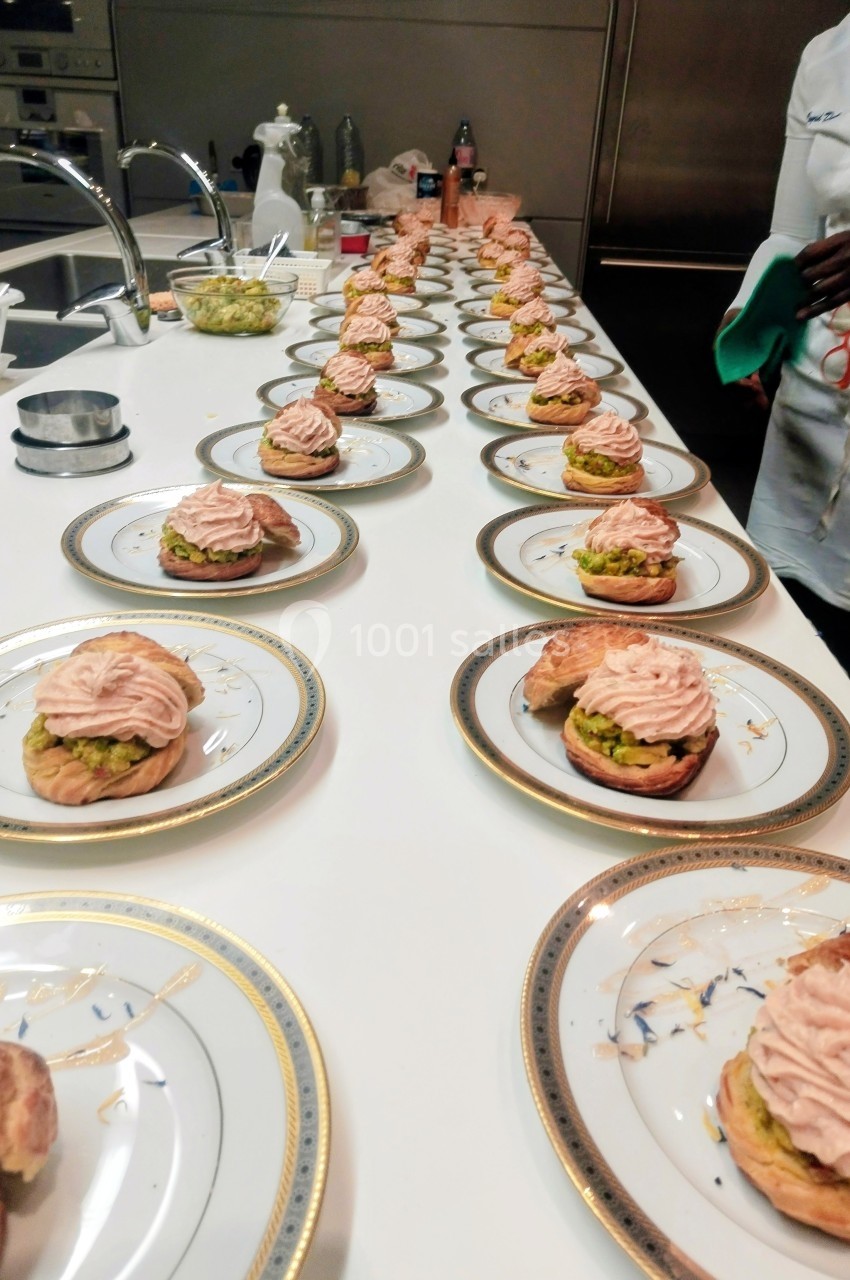 Assiettes alignées sur un plan de travail, chacune contenant un choux garni de mousse rose et d'une base verte.