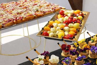 Petits pains garnis de pastrami, germes de luzerne et graines noires, disposés sur un plateau en métal.